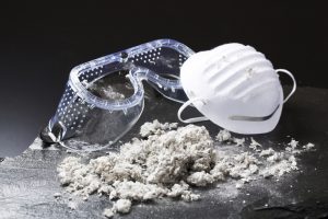 Protective mask and safety goggles next to asbestos fibers, illustrating risks of asbestos exposure in older buildings
