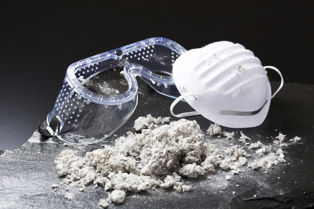 Protective mask and safety goggles next to asbestos fibers, illustrating risks of asbestos exposure in older buildings