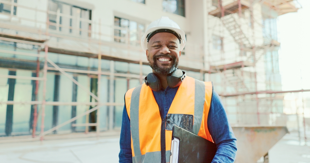 Smiling contractor in safety vest and hard hat standing at a commercial renovation site