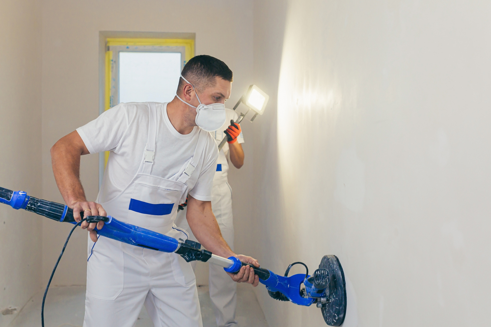 Plasterer smoothes the wall surface with a wall grinder