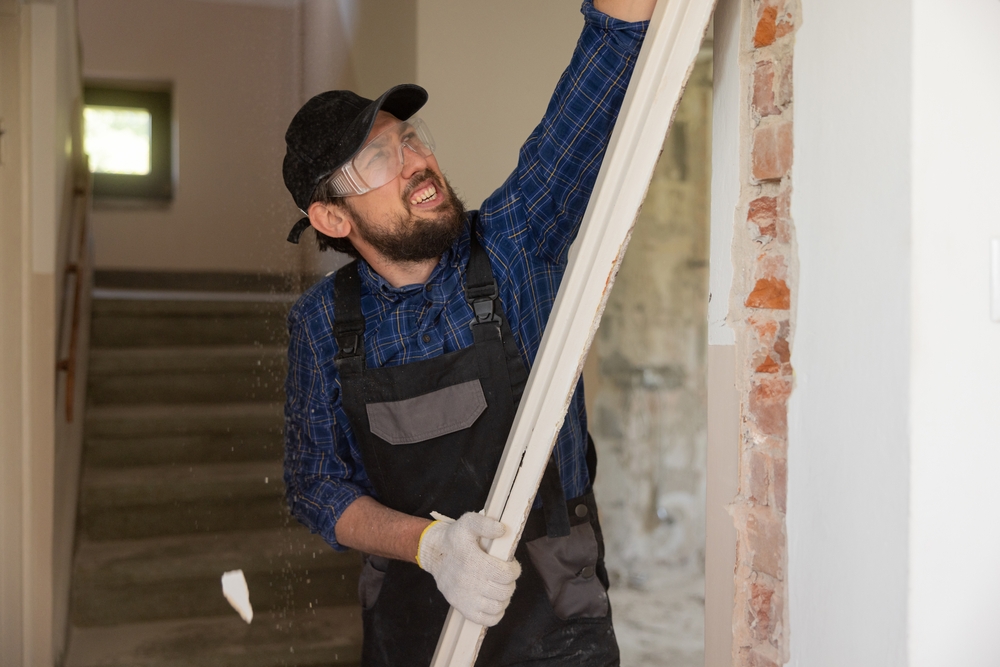 Certified contractor removing old frame from door in a commercial building