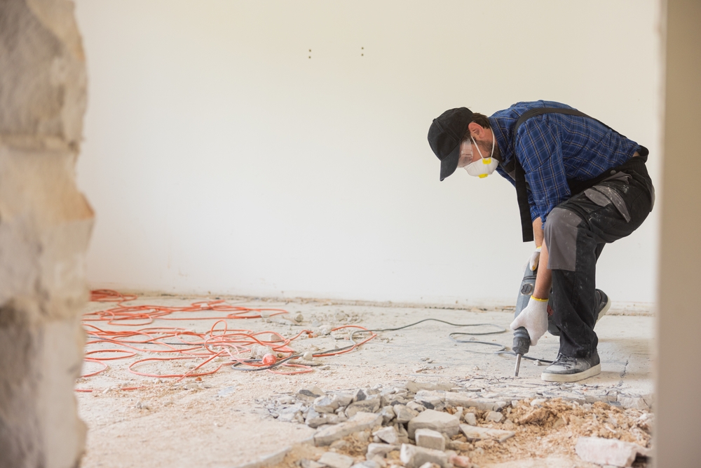 Contractor using a hand-held demolition hammer and breaker to remove old floor tiles